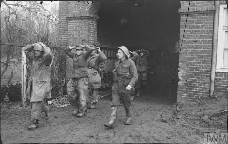 
A Canadian soldier escorts captured German parachute troops during fighting near Uedem, 28 February 1945. 