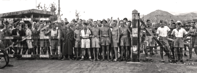 Les prisonniers canadiens et britanniques attendent d’être libérés par la compagnie de débarquement du NCSM Prince Robert, à Hong Kong, en aout 1945. [PHOTO : OM JACK HAWES, BIBLIOTHÈQUE ET ARCHIVES CANADA—PA114811]
