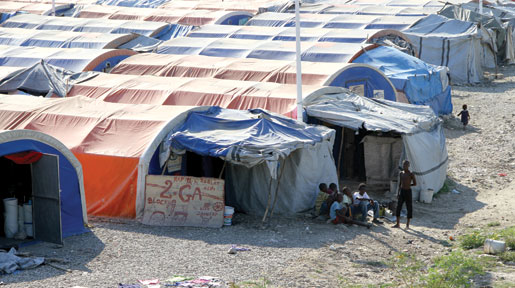 Des enfants, dont un en bas âge, se tiennent à l’ombre dans un camp pour personnes déplacées à l’intérieur du territoire. [PHOTO : DAN BLACK]