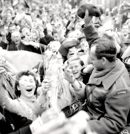 Les joyeux citoyens hollandais tendent la main à un soldat canadien en célébration de la libération, en mai 1945. [PHOTO :  ALEXANDER STIRTON, BIBLIOTHÈQUE ET ARCHIVES CANADA — PA134376]