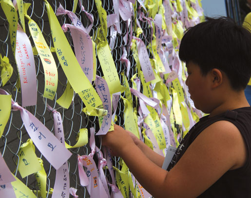 Des enfants fixent des messages de paix au musée national d’histoire contemporaine de Corée. [Photo : Tom MacGregor]