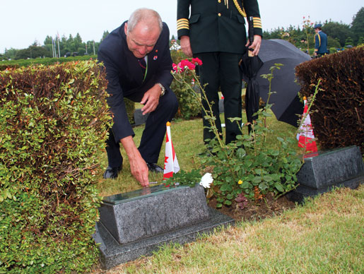 Le sénateur Joseph Day dépose une fleur sur la tombe du simple soldat Joseph Hearsey. [Photo : Tom MacGregor]