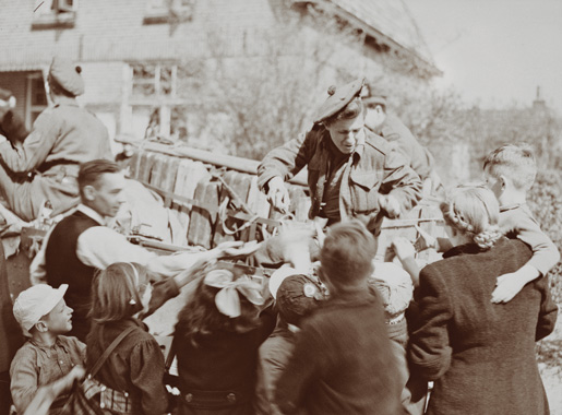 Un soldat du Stormont, Dundas and Glengarry Highlanders distribue des bonbons à des habitants de Bathmen, ville de  l’est des Pays-Bas, le 9 avril 1945. [MDN/BAC/PA-137908]