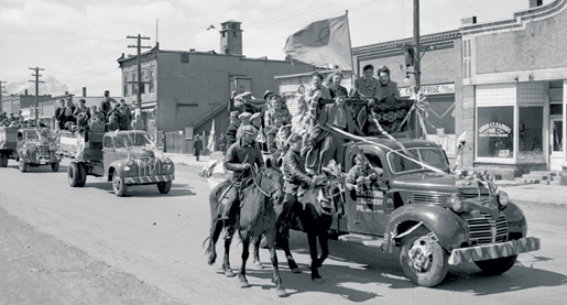 Des camionnettes décorées et des cavaliers se joignent à un défilé de la victoire à Blairmore, en Alberta. [MUSÉE GLENBOW/NC-54-2123]