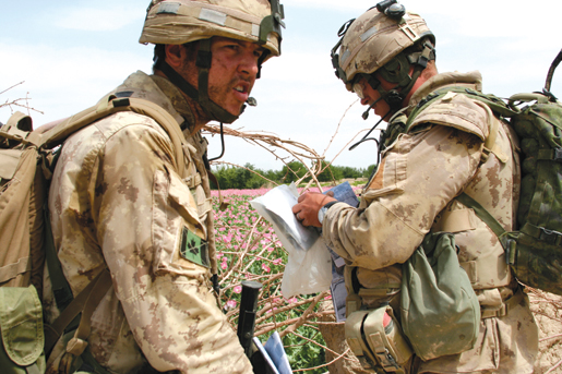 Capt. Bob Barker (left) stops the patrol as another Bravo Company soldier checks the map. [PHOTO: ADAM DAY]