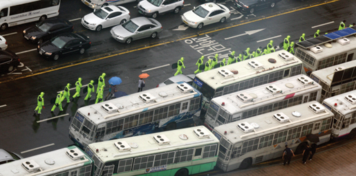 South Korean riot police in rain gear rush to meet protesters in Seoul. [PHOTO: TOM MACGREGOR]
