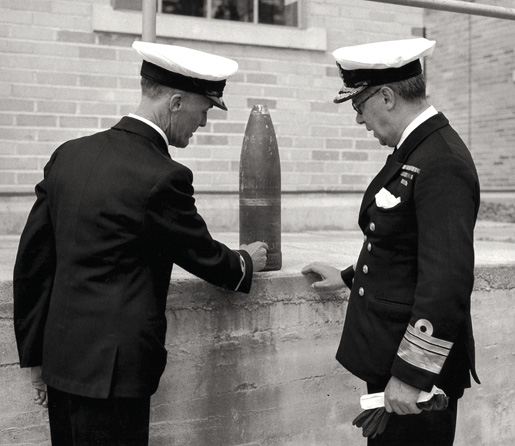Naval staff inspect a shell from Estevan Point, B.C. [PHOTO: GERALD THOMAS RICHARDSON, NATIONAL DEFENCE, LIBRARY AND ARCHIVES CANADA—PA134083]