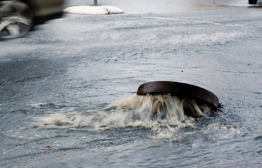 A storm sewer blows its cover during a rainstorm. [PHOTO: ©iStockphoto/Dizzy]