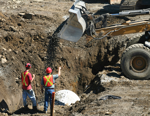 Workers help install a concrete pipe. [PHOTO: ©iStockphoto/kozmoat98]