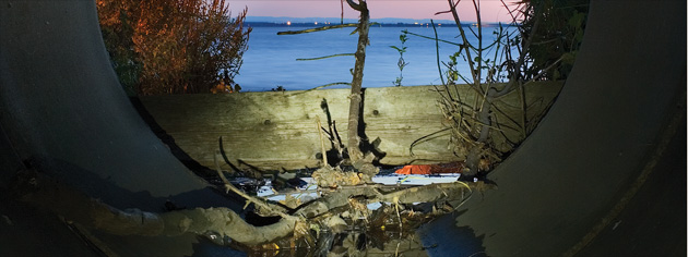 Debris collects at the mouth of a storm drain along the St. Lawrence River. [PHOTO: ANDREW EMOND, WWW.WORKSONGS.COM]