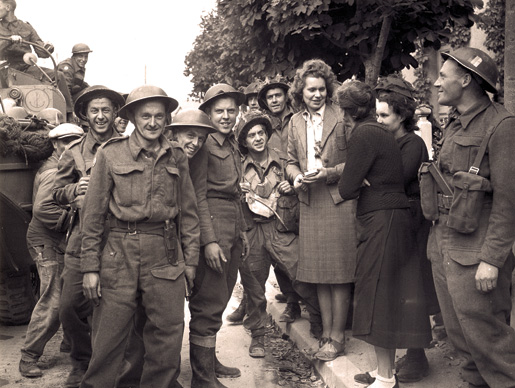 French women greet Canadian soldiers in a liberated town, June 10, 1944. [PHOTO: LT. DONALD I. GRANT, LIBRARY AND ARCHIVES CANADA–PA137978]