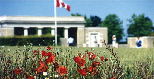 The Canadian flag flies over fields of poppies at Bretteville-sur-Laize Canadian War Cemetery, France, in 1991. [PHOTO: TOM MacGREGOR]
