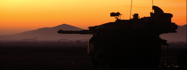 An orange sky and the mountainous terrain of Afghanistan provide a backdrop for a military vehicle. [PHOTO: COMBAT CAMERA/DND]
