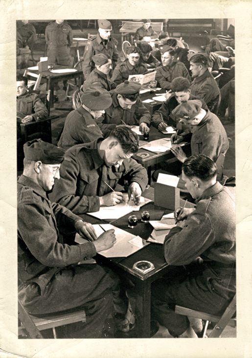 Soldiers take advantage of  the writing facilities inside a Canadian Legion recreation hut in England. [PHOTO: A. LOUIS JARCHE]