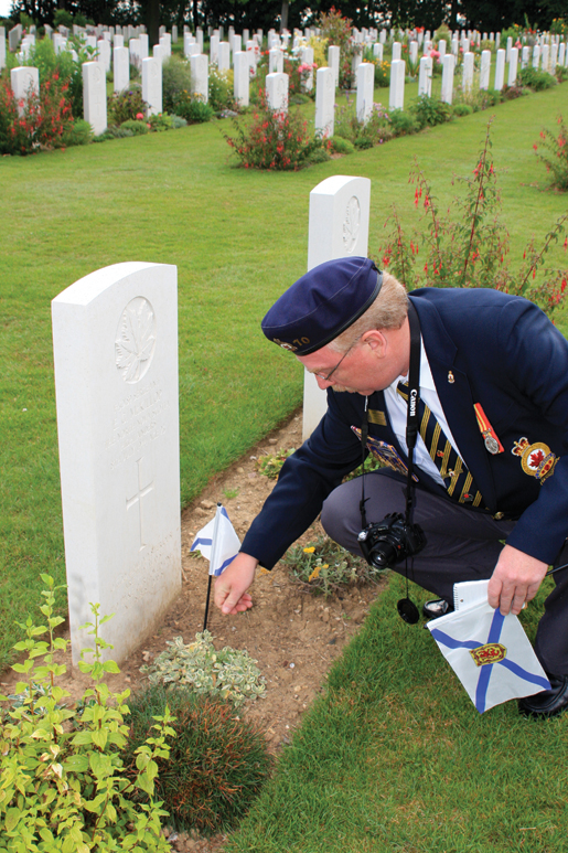 David Andrews places a provincial flag on the grave of a fellow Nova Scotian at Beny-sur-Mer Canadian War Cemetery in Normandy. [PHOTO: SHARON ADAMS]