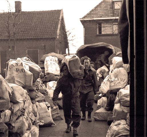 Members of the Pioneer Corps unload Christmas mail at 2 Canadian Corps Army Post Office in  the Netherlands, December 1944. [PHOTO: B.J. GLOSTER, LIBRARY AND ARCHIVES CANADA—PA137637]