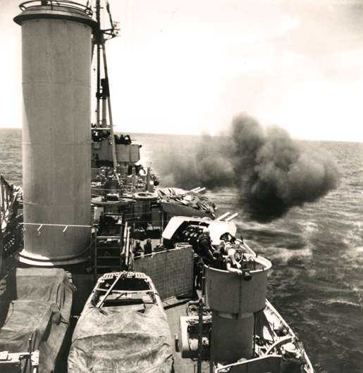 HMCS Uganda fires her guns on a Japanese airfield, May 1945. [PHOTO: GERALD MOSES, LIBRARY AND ARCHIVES CANADA—PA136073]