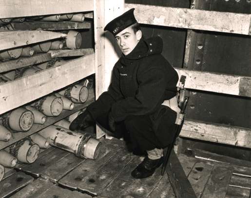 A rating of the Naval Control of Shipping Service inspects a cargo of shells aboard a wartime merchant ship at Halifax. [PHOTO: LIBRARY AND ARCHIVES CANADA—PA104377]