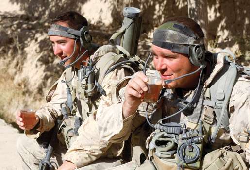 Sgt. C.J. Flach (right) and M.Cpl. Paul Guilmane drink tea with a villager. [PHOTO: ADAM DAY]