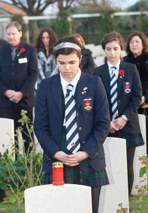 Students from CCI Renaissance School place candles on headstones. [PHOTO: TOM MacGREGOR]
