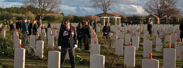 Veterans and students walk through the Moro River Canadian War Cemetery following a candlelight ceremony. [PHOTO: TOM MacGREGOR]