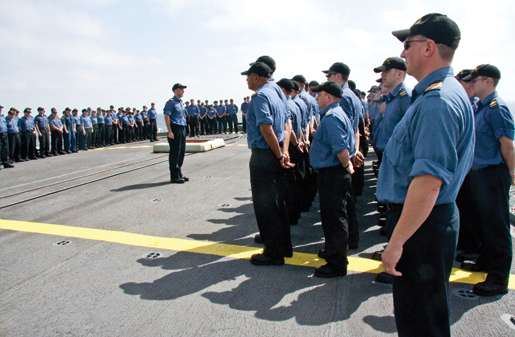 The ship’s company musters on the flight deck for an awards ceremony. [PHOTO: DAN BLACK]