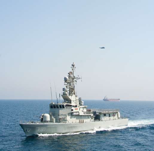 A U.A.E. naval vessel in manoeuvres with Fredericton and her Sea King (above). Passing by is one of many cargo vessels that transit the area. [PHOTO: DAN BLACK]