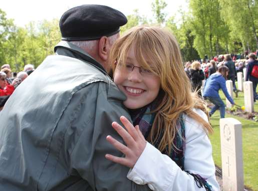 Veteran Stanley Fields of Ottawa hugs a Dutch child at Holten Canadian War Cemetery.  [PHOTO: SHARON ADAMS]