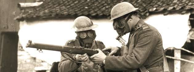 With their respirators on, two Canadian soldiers examine a Lee-Enfield, March 1917. [PHOTO: WILLIAM IVOR CASTLE, LIBRARY AND ARCHIVES CANADA—PA001027]
