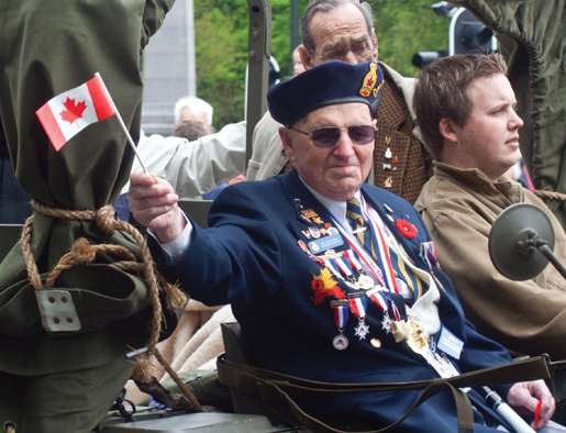 John Gay of Fredericton Branch waves to the crowd. André Montcalm (right) at his brother’s grave.  [PHOTO: TOM MacGREGOR]
