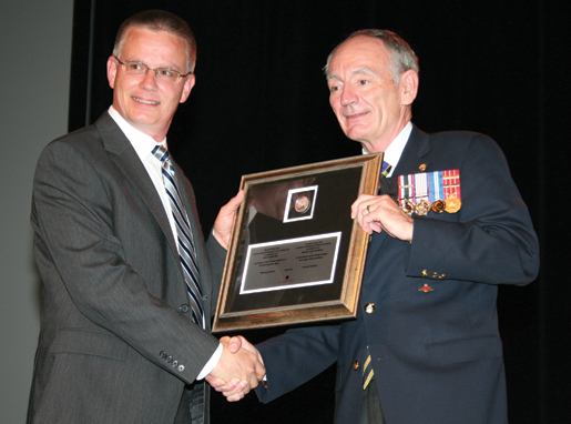 Mark Neuendorff (left), director of the Royal Canadian Mint’s Winnipeg facility, presents one of four framed commemorative silver dollars in honour of the navy’s centennial to Dominion Grand President Larry Murray. [PHOTO: JENNIFER MORSE]