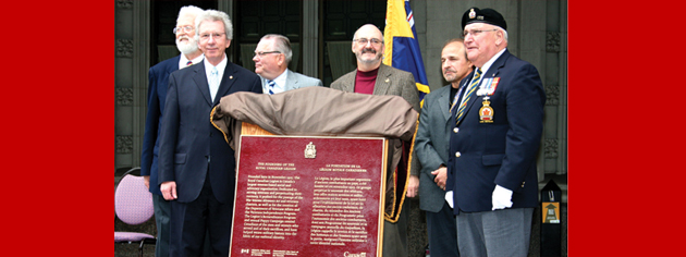 Veterans Affairs Minister Jean-Pierre Blackburn (front left) and Dominion President Wilf Edmond (front right) unveil the plaque recognizing the founding of The Royal Canadian Legion as a historic event. [PHOTO: JENNIFER MORSE]
