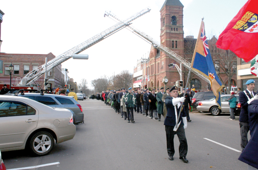The parade marches under the firefighters’ arch. [PHOTO: TOM MacGREGOR]