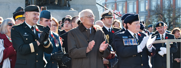 (From left) Canada’s Chief of Defence Staff General Walt Natynczyk, Vincent Girouard, husband of Silver Cross Mother Mabel Girouard, and Royal Canadian Legion Dominion President Pat Varga applaud the veterans as they march past. [PHOTO: METROPOLIS STUDIO]