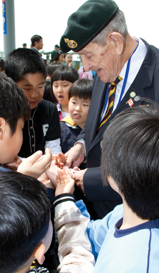 Veteran Donald Doan of Windsor, Ont., hands out souvenirs to schoolchildren. [PHOTO: DAN BLACK]