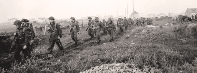 Canadian soldiers advance during Operation Spring, July 25, 1944. [PHOTO: KEN BELL, LIBRARY AND ARCHIVES CANADA—PA131378]