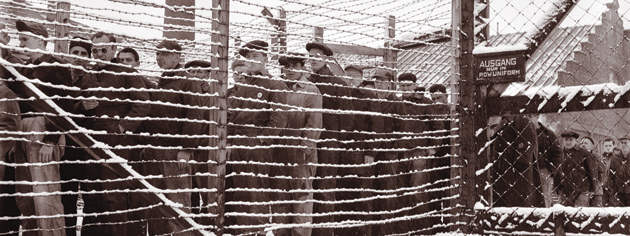 Prisoners look out from behind barbed wire at Sherbrooke, Que., in 1945. [PHOTO: LIBRARY AND ARCHIVES CANADA—PA163788]