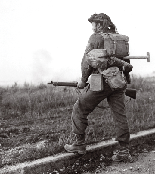 A soldier waits for the artillery barrage to clear before moving forward. [PHOTO: KEN BELL, LIBRARY AND ARCHIVES CANADA—PA163403]