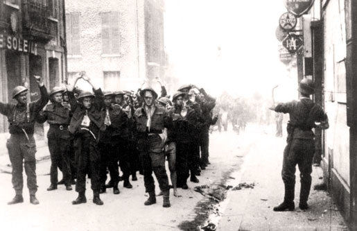 A German soldier points to Canadian soldiers lined up in the street after being captured. [PHOTO: REGIMENTAL SENATE OF THE ROYAL HAMILTON LIGHT INFANTRY]
