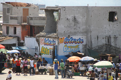 Haitians visit a market outside Cité Soleil. Note the bullet holes on the side of the earthquake-damaged buildings. [PHOTO: DAN BLACK]