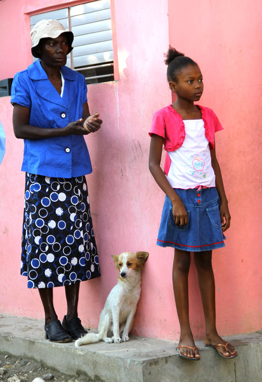 A woman, a girl and dog watch as Canadian visitors learn more about the orphanage. [PHOTO: DAN BLACK]