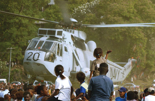 Crowds wave to a Royal Australian Navy Sea King helicopter during the Regional Assistance Mission to the Solomon Islands in 2003. [PHOTO: WO2 GARY RAMAGE]