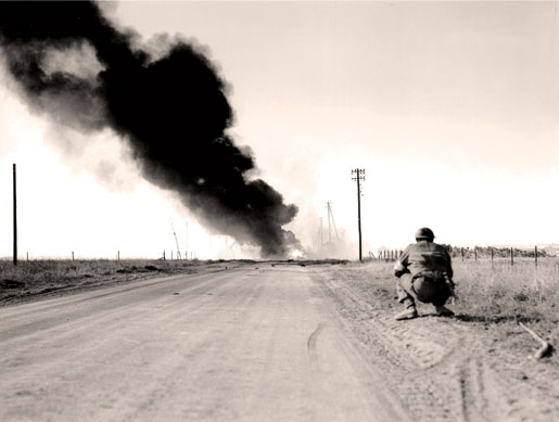 Smoke from burning vehicles blackens the sky above the Caen-Falaise Road near Hautmesnil, France, August 1944. [PHOTO: DONALD GRANT, LIBRARY AND ARCHIVES CANADA—PA191881]