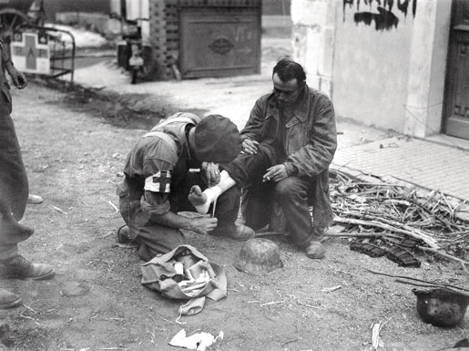 A Canadian soldier treats a wounded German prisoner at Trun, Aug. 19, 1944. [PHOTO: DONALD I. GRANT, LIBRARY AND ARCHIVES CANADA—PA188905]
