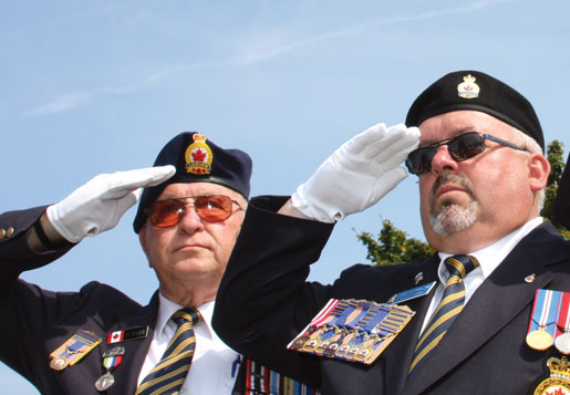 Sam Newman and Legion Dominion Vice-President Dave Flannigan salute at Tyne Cot Cemetery. [PHOTO: SHARON ADAMS]