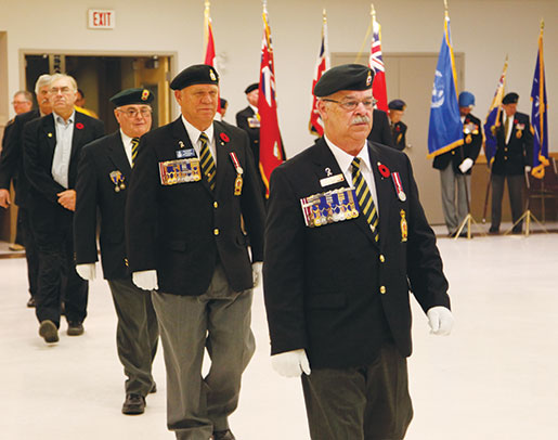 Dominion representative Paul Poirier leads Manitoba-Northwestern Ontario Command Past President Rick Bennett (second from right) and other guests towards the stage. [PHOTO: ADAM DAY]