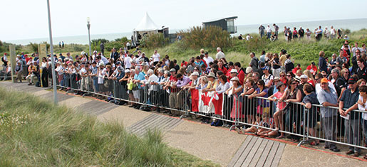 An overflow crowd of French residents and Canadian tourists line a fence outside Juno Beach Centre awaiting the official Canadian D-Day ceremony. [PHOTO: SHARON ADAMS]