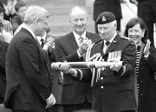 The last Canadian flag flown in the Afghanistan mission passes from Harper to Johnston. [PHOTO: ADAM DAY]
