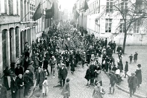 Canadians soldiers and Belgians march through the streets of Mons on the morning of November 11, 1918. [PHOTO: LIBRARY AND ARCHIVES CANADA—PA003547]