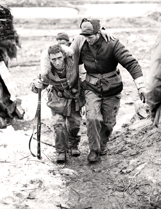 Private Morris Piche of 2nd Battalion, PPCLI, is helped to an aid station near Kapyong by Lance Corporal Bill Chrysler, 1951.[PHOTO: IMPERIAL WAR MUSEUM—MH033026]